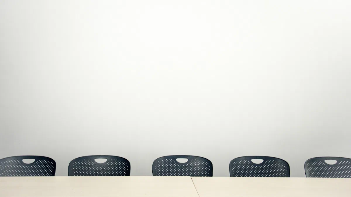 Three black chairs around a small table in an empty white meeting room