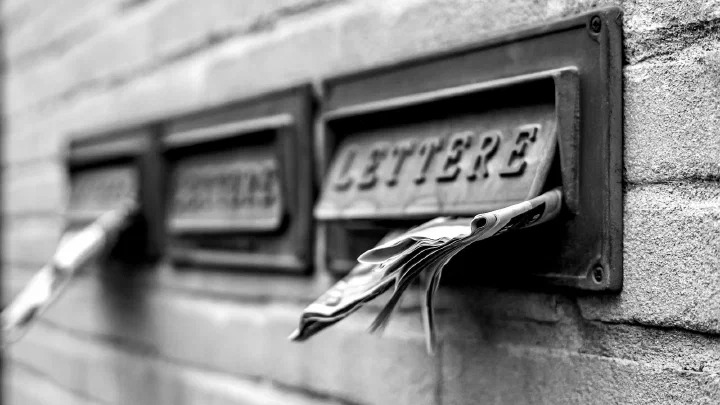 Three closed metal letterboxes mounted on a brick wall