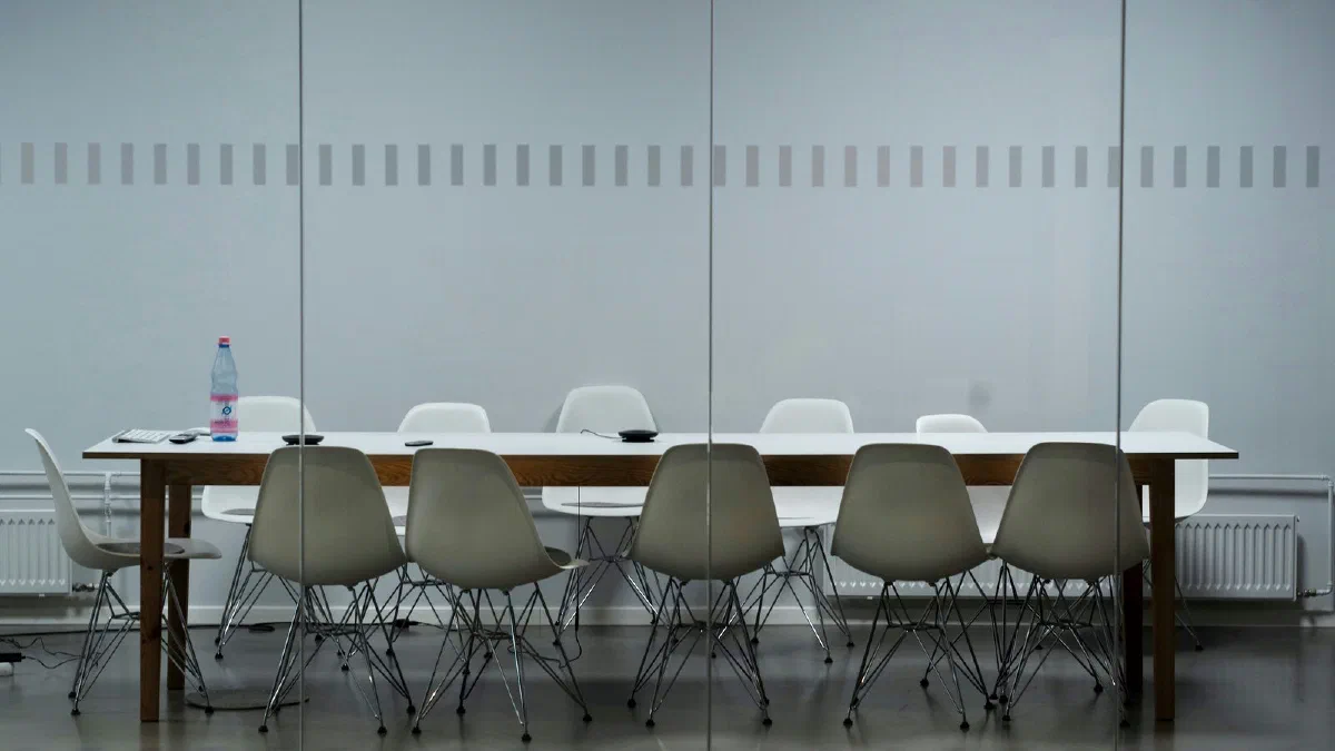 A long empty meeting table with chairs around it
